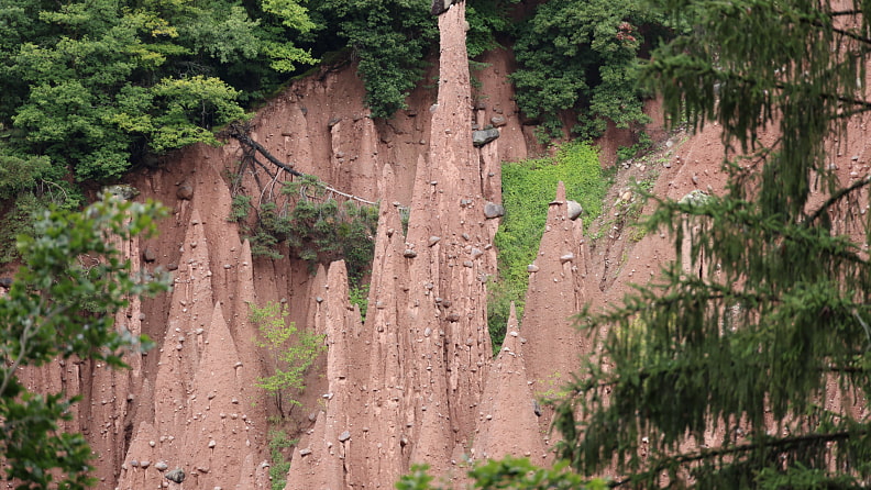 Wir besuchen Erdpyramiden. Die Steine an der Spitze schützen den Lehm darunter vor Verwitterung.